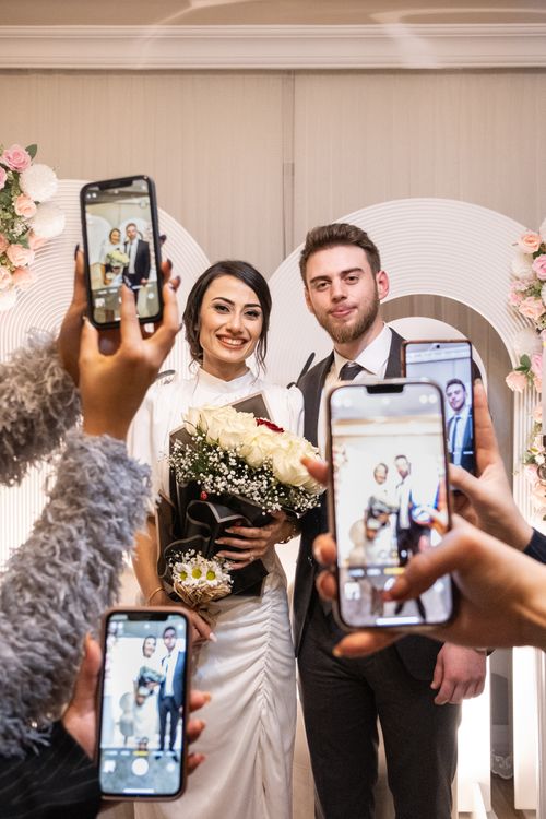 Mladenci sa gostima koji ih fotografišu telefonima